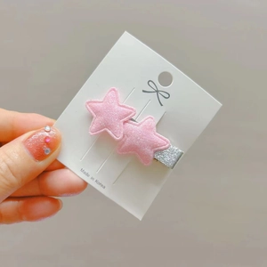 Detail of glittery pink star hair clips on a white display card with a metal base