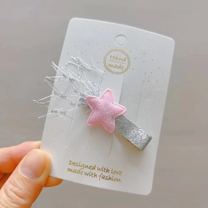 Pince à cheveux étoile rose pailletée avec pompons argentés sur carte blanche