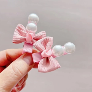 Detailed macro view of pink ribbon bow hair clips with decorative white pearls