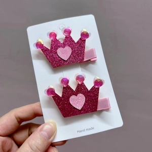 Detailed close-up of pink glitter crown hair clips with heart accents for girls