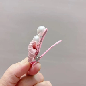 Detail of pink fabric flower hair clip with pearls and fabric-wrapped duckbill clip