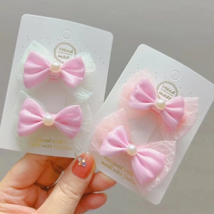 Vue détaillée des barrettes à nœuds en satin rose avec perles sur support carton