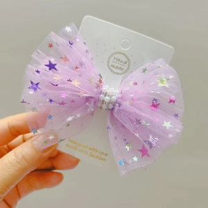 Détail d'une pince à cheveux en tulle violet avec étoiles dorées et perles blanches