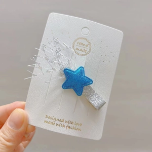 Détail d'une pince à cheveux étoile bleue pailletée avec franges sur carte blanche