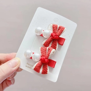 Detailed macro view of red and white knitted bow hair clips with faux pearls on a display card