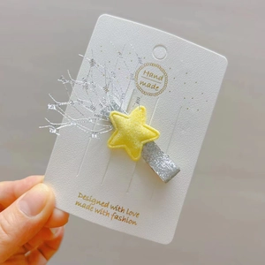 Détail d'une pince à cheveux étoile jaune avec finition pailletée argentée sur carte