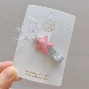 Détail de la barrette étoile rose pailletée avec pompons argentés sur carte blanche