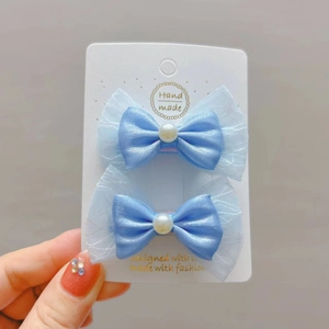Vue détaillée de barrettes à nœuds en satin bleu clair et dentelle avec perles
