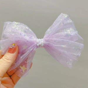Détail de la barrette nœud en tulle violet avec étoiles et perles blanches