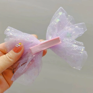 Détail d'une barrette en tulle violette avec étoiles pailletées, perles et ruban rose