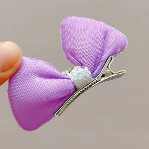 Close-up of a purple sequin bow hair clip with sparkling rhinestones and metal duckbill clip