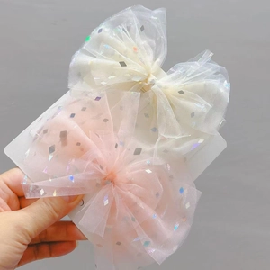Dettaglio di fiocchi per capelli per bambini in rete con paillettes bianchi e rosa