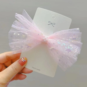 Vue détaillée du nœud en tulle rose avec paillettes et perles sur barrette