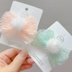 Detalle de pinzas para el cabello con lazo de organza y pompones de piel sintética suave