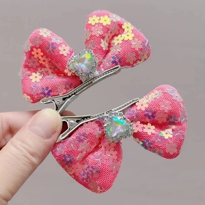 Detailed macro view of pink bow hair clips with heart-shaped gems and sequins