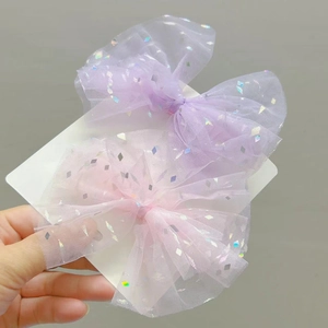 Dettaglio di fermagli a fiocco in tulle con paillettes rosa e lavanda pastello