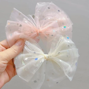 Dettaglio di fiocchi per capelli in tulle rosa e crema con paillettes per bambine
