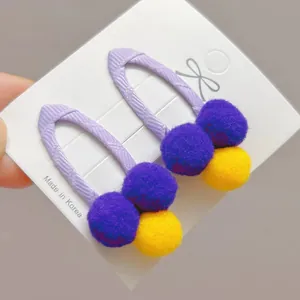 Detail view of purple knitted hair clips with colorful plush pom poms for girls