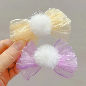 Detalle de las horquillas de lazo de tul con pompones blancos de piel en colores pastel