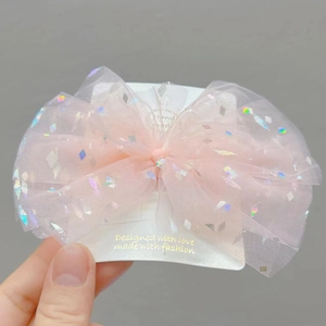 Dettaglio del fiocco per capelli in tulle rosa con paillettes olografiche su scheda