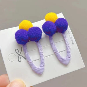 Detail of yellow and purple pompom hair clips on a white display card for girls