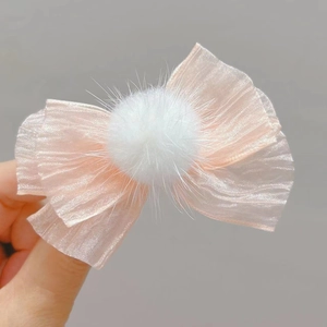 Detalle de la pinza de pelo con lazo de seda rosa y pompón blanco suave