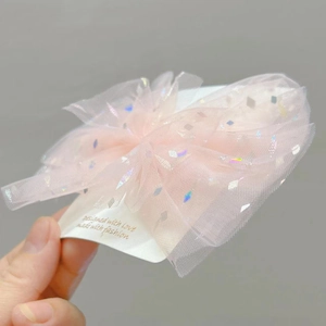 Dettaglio del fiocco in tulle rosa con motivi a rombi di paillettes olografiche