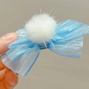 Detalle de la pinza para el pelo con lazo de malla azul claro y pompón de peluche