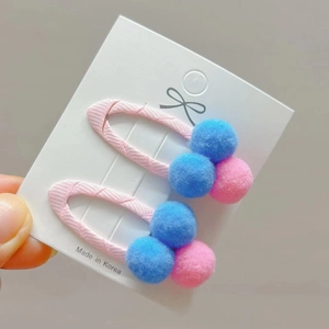Kids hair clips set featuring pink and blue fuzzy pom-poms with ribbon-wrapped metal BB clips