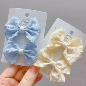Détail de nœuds de cheveux en tissu bleu et beige pour filles sur carte blanche