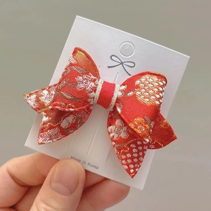 Dettaglio di un fermaglio per capelli rosso in stile etnico con ricami floreali