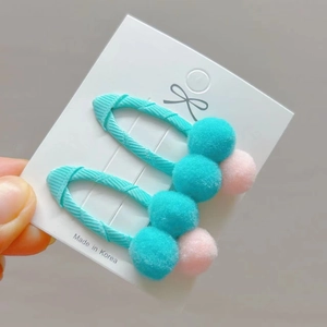 Pink and blue pom-pom hair clips set on a display card for girls' hair styling