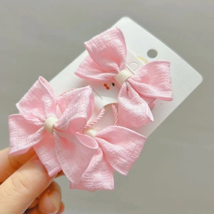 Détail de deux élastiques à cheveux rose avec nœuds en tissu sur carte blanche