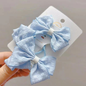 Détail de deux chouchous à nœuds en tissu bleu clair avec texture sur carte blanche