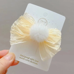 Detalle del clip de pelo coreano con lazo de organza beige y pompón de piel blanca