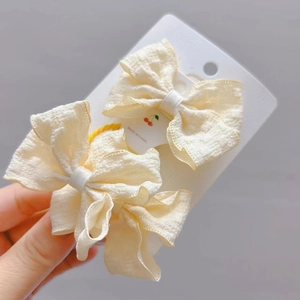 Vue détaillée de deux nœuds papillon en tissu crème texturé pour cheveux de filles