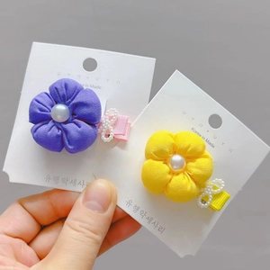 Detail of purple and yellow fabric flower hair clips with pearls and infinity charms