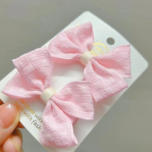 Gros plan de barrettes à nœud en tissu rose pour filles sur carte de support
