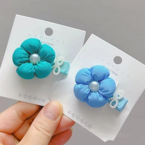 Detail of fabric flower hair clips with faux pearls and bows on a display card