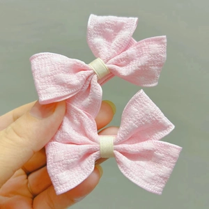 Détail des barrettes à cheveux avec nœud en tissu rose et texture tissée pour fillettes