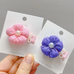 Detail of pink and purple fabric flower hair clips with pearls on a display card
