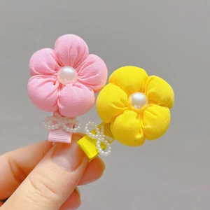 Close-up of fabric flower hair clips with faux pearls and ribbon-wrapped metal grips