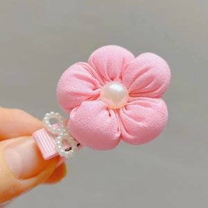 Close-up of a pink fabric flower hair clip with pearl center and bow detail