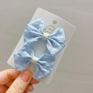 Lot de deux barrettes nœuds en tissu bleu ciel pour filles avec texture plissée sur carte