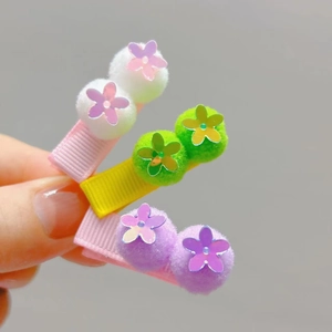 Detailed close-up of three colorful pompom and sequin flower hair clips for girls