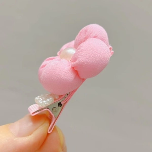 Close-up of a pink fabric flower hair clip with a pearl center and beaded metal grip