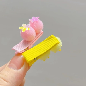 Detail of pink and yellow pom pom hair clips with glitter flower sequins on ribbon wraps
