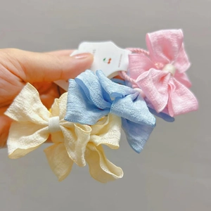 Détail de chouchous à nœuds en tissu rose bleu et jaune avec texture pour les filles