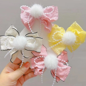 Dettaglio di fermagli per capelli con fiocchi fatti a mano, pompon e catenelle di perle