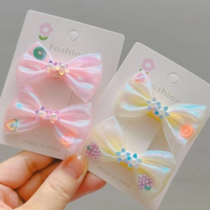 Détail de barrettes à nœuds en maille irisée avec perles et fleurs pour fillettes